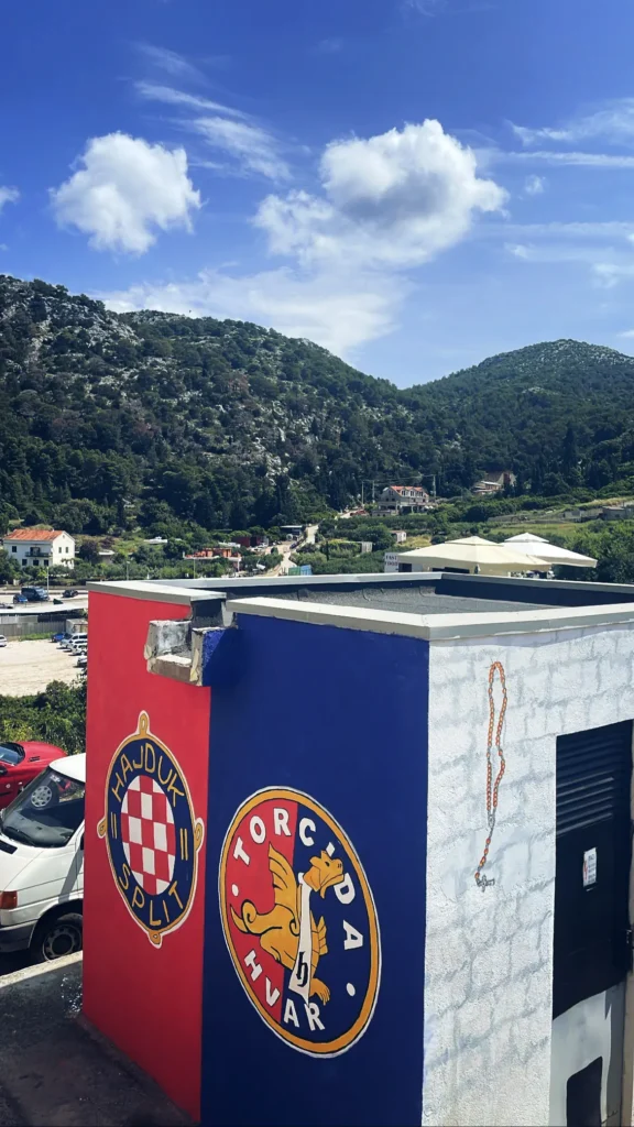 Torcida Split Hvar y escudo del Hajduk Split en forma de graffiti en una pared bicolor rojo-azul