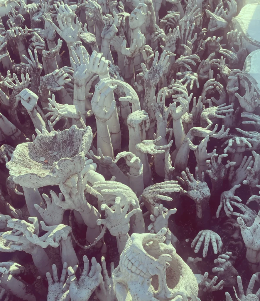 Manos blancas emergiendo del suelo en el Templo Blanco de Chiang Rai